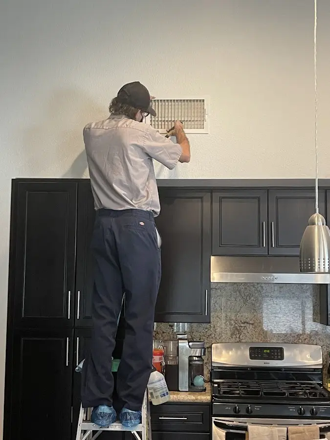 Technician inspecting an air vent during HVAC service in Santa Cruz